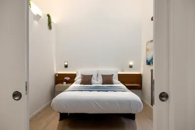 a bedroom with a large bed with white sheets at Roccella Apartments in Palermo