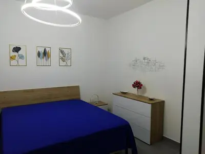 a bedroom with a blue bed and a white wall at Casa Nino' in Palermo