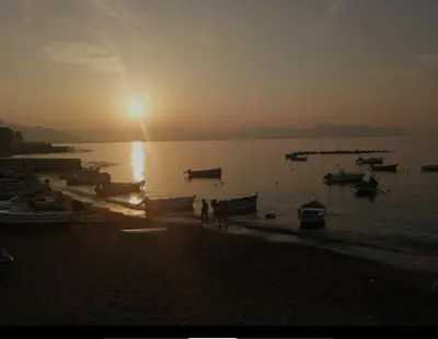 a sunset over a beach with boats in the water at La Riva - Seashore in Bagheria