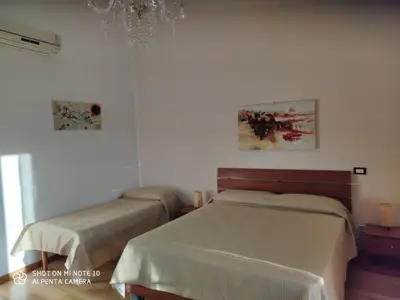a bedroom with two beds and a chandelier at Casa Anna in Carini