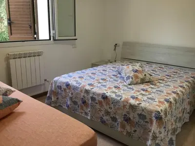 a bedroom with a bed with a floral comforter at Casa Amuri in Scopello