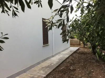a white wall with a window with a shutter at Casa Amuri in Scopello