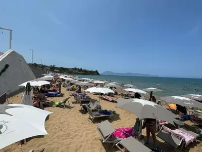 a group of people sitting on a beach with umbrellas at Casa di Pippo in Trappeto