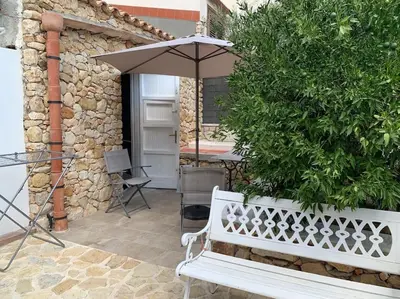 a white bench sitting next to a table with an umbrella at Scopello - Finestra sul cortile in Scopello