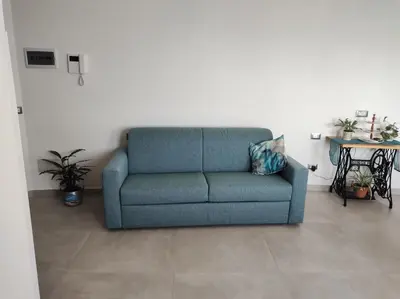a blue couch in a living room with a table at RineddaHouse Arenella - Vista Mare Panoramica a Palermo con Parcheggio privato in Palermo