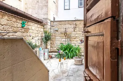 an outdoor patio with chairs and a stone wall at GuestHost - Near Palermo's Historic Heart - Apt with Courtyard in Palermo