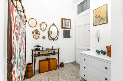 a bathroom with white walls and a table and mirror at GuestHost - Near Palermo's Historic Heart - Apt with Courtyard in Palermo