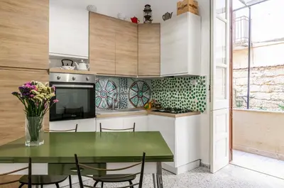 a kitchen with a green table and chairs at GuestHost - Near Palermo's Historic Heart - Apt with Courtyard in Palermo