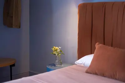 a vase of flowers sitting on a table next to a bed at Belmonte LR Collection in Palermo