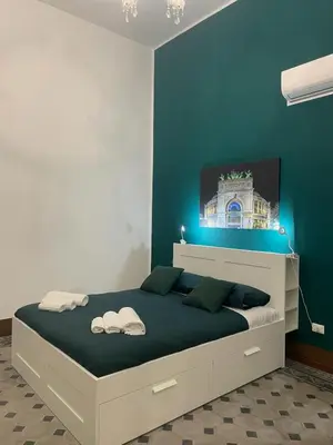 a bedroom with a large bed with a blue wall at Ai Crociferi affittacamere in Palermo
