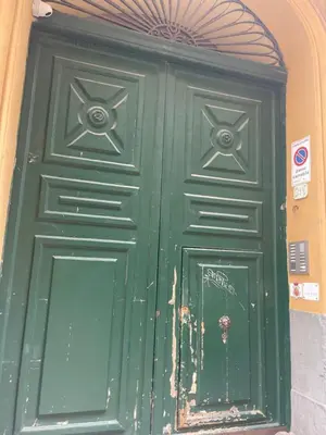 a green door on a building with a sign on it at Ai Crociferi affittacamere in Palermo