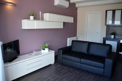 a living room with a black couch and a tv at Palermo Holidays in Mondello
