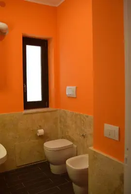 an orange bathroom with a toilet and a window at Palermo Holidays in Mondello