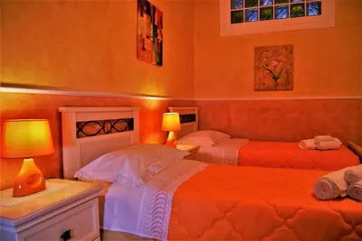 two beds in a room with orange walls at B&B Oleaster - Bolognetta in Bolognetta