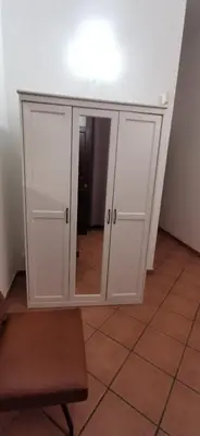 a white cabinet with a mirror and a stool at Casa Bellini in Palermo