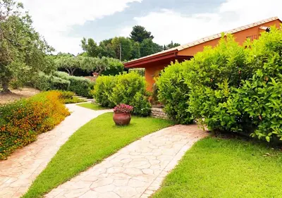 a garden with a stone path and a house at Villa Cattleya in Campofelice di Roccella