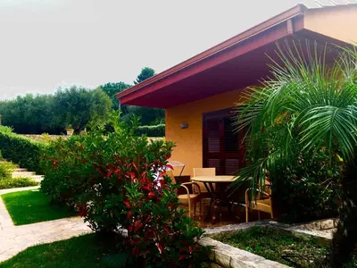 a house with a table and chairs in a garden at Villa Cattleya in Campofelice di Roccella