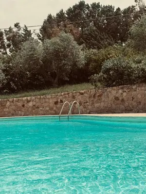 a swimming pool with blue water and a stone wall at Villa Cattleya in Campofelice di Roccella
