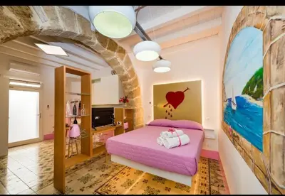 a bedroom with a pink bed in a room with a stone wall at Casa Rosa Castellammare del Golfo in Castellammare del Golfo