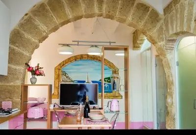 an archway in a room with a table and a television at Casa Rosa Castellammare del Golfo in Castellammare del Golfo
