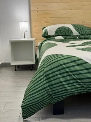 a bed with a green and white blanket and a night stand at A CASA DI IDA in Palermo