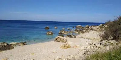 a beach with rocks and the ocean on a sunny day at Villa Chifeci Scopello - Appartamento Verde in Scopello