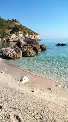 a beach with rocks and the ocean on a sunny day at Villa Chifeci Scopello - Appartamento La Zàgara in Scopello