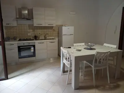 a kitchen with a table and chairs and a refrigerator at L'Aurora in Porticello