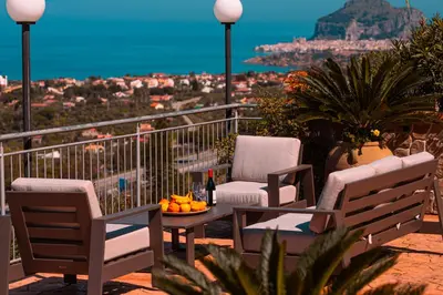 a balcony with chairs and a table with fruit on it at Villa Le Terrazze in Cefalù