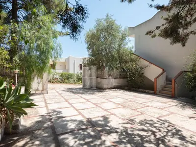 a courtyard with a gate and trees in front of a building at [Baia di Guidaloca] Villino Scopello Free Parking in Scopello