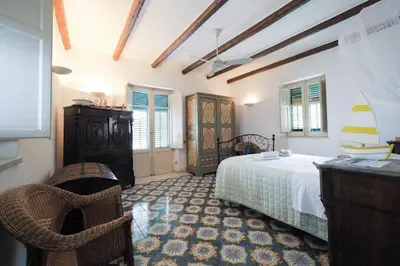 a bedroom with a bed and a dresser and windows at Casetta Bianca Sant'Elia in Porticello