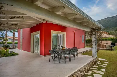 a red house with a table and chairs on a patio at Villa Jacqueline con piscina privata 8 posti letto in Scopello