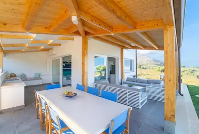 a kitchen and dining room with a white table and chairs at Villa Majestatis con piscina privata in Scopello
