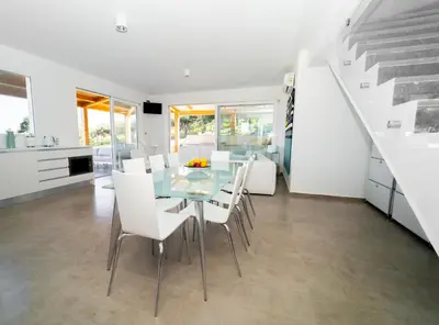 a dining room with a glass table and white chairs at Villa Majestatis con piscina privata in Scopello