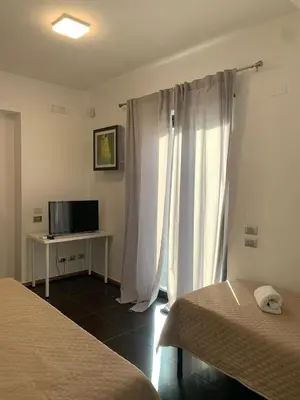 a hotel room with two beds and a television at Villa Rubino in Isola delle Femmine