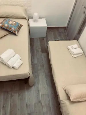 a small room with two beds and a table at Silvia's House in Castellammare del Golfo