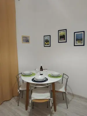 a dining room table with chairs and a white wall at A casa di Elvira in Palermo