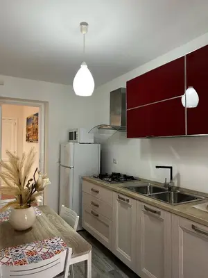 a kitchen with red cabinets and a table and a refrigerator at Maquè apartments in Palermo