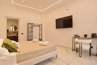 a bedroom with a bed and a table and a television at FLA' Suite Deluxe in Terrasini
