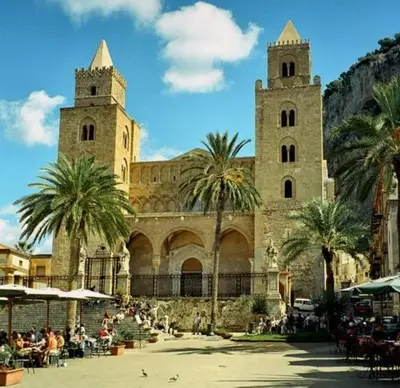 a building with two towers with palm trees and people at Vacanze Palermitane in Palermo