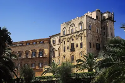 a large brick building with palm trees in front of it at Vacanze Palermitane in Palermo