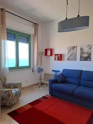 a living room with a blue couch and a red rug at La Finestra sul Golfo in Castellammare del Golfo