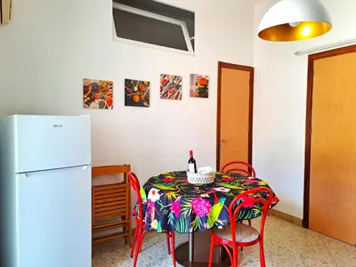 a kitchen with a table and a refrigerator at La Finestra sul Golfo in Castellammare del Golfo