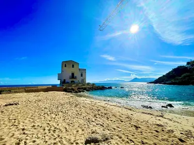 a building on a beach next to the water at Bellavista in Santa Flavia