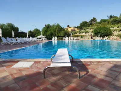 a white bench sitting in front of a swimming pool at Villa Agae in Trabia