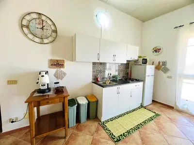 a kitchen with white cabinets and a sink and a table at Tri Ri Coppe in Cinisi