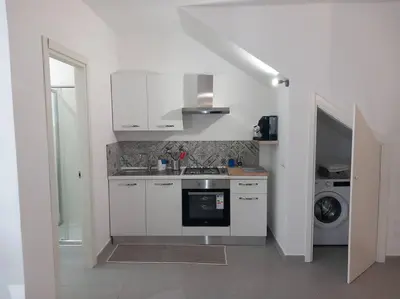 a white kitchen with a sink and a dishwasher at Villa Costa Mondello in Palermo