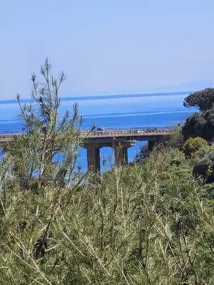 a bridge on a hill with the ocean in the background at Nika Holiday Home in Casteldaccia