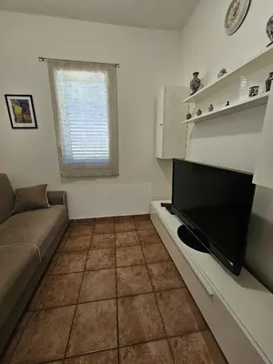 a living room with a couch and a flat screen tv at Nika Holiday Home in Casteldaccia