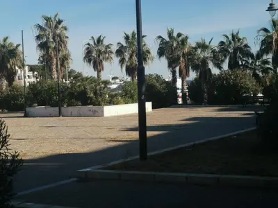 a parking lot with palm trees and a light pole at Casa vacanze Haliotis in Isola delle Femmine